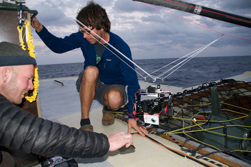 Joe Brock and Don Montague test a gyro-stabilized camera orientation platform. The platform is suspended from the main kite line and winched up independently using a motor. In this configuration, the small white camera sends live video back to the team via a wireless connection that is viewed on a handheld device or laptop computer. They can control the frame orientation and black camera remotely over the wireless connection.