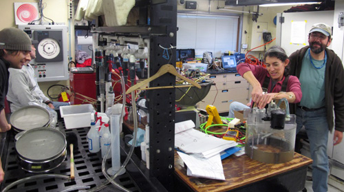 Making the most of the working space on the Western Flyer. The left side has sieves, spray bottles and buckets ready for processing gallons of splatter-prone deep-sea mud. On the right, Alana Sherman and Paul McGill check the electronics that run the Rover.