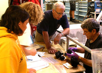 From left to right, Dorsey Wanless, Jenny Paduan, Mike Perfit, and Dave Clague sort rock samples from the ROV's sample drawer after the dive. We rely on our notes and video framegrabs taken during the dive to distinguish the samples and know which drawer compartments they were placed into when they were collected, so we can be sure which rock came from which flow or pillow mound for our subsequent analyses. These fragile, glassy lavas often break into several pieces, and we don't want to accidentally mix and match.