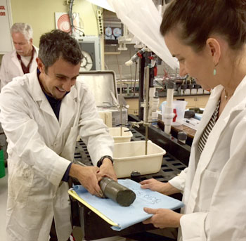 Aaron Micallef extrudes the sediment from a push core while Eve Lundsten holds a tray on which she will split the core in half and photograph it.