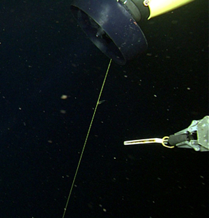 The ROV manipulator grips a knife and approaches the line caught on the AUV.
