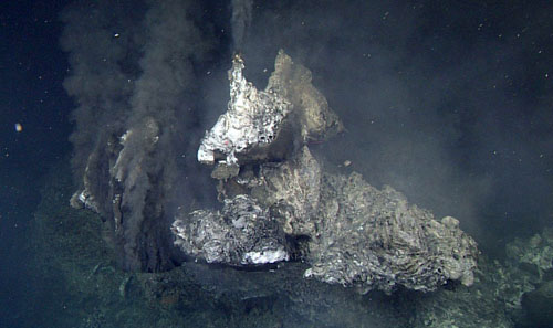 A sulfide flange sticks out toward the ROV at the top of an 18-meter-high black smoker in the newly discovered vent field at Alarcón Rise. Hot vent fluids are exiting the structure underneath this flange (as well as from a more classic chimney orifice at the top), ponding underneath,