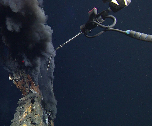 The tip of a high-temperature thermocouple probe is about to be inserted into the orifice of a black smoker. Temperatures of the spewing hydrothermal fluids exceeded 350 degrees Celsius (662 degrees Fahrenheit).