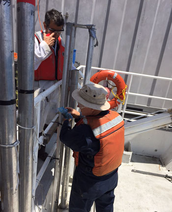 Aaron Micallef and Brian Edwards process the vibracores on the back deck, cutting off the excess tube so they can then insert the syringes to extract the water within the sediment (pore water).