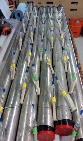 Syringes are inserted into the core tube to extract the pore water for chemical analysis later in the lab.