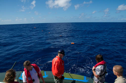 Mast and floats stream out beyond the fantail of Lone Ranger as the Sargasso Deep-Sea Observatory goes into the ocean.