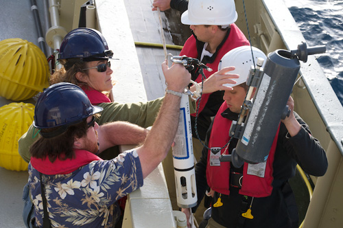 The hydrolab and Niskin bottle are being lifted over the wall for deployment. The ends of the Niskin bottle are held open by a spring and will be triggered closed when the bottle reaches the desired depth.