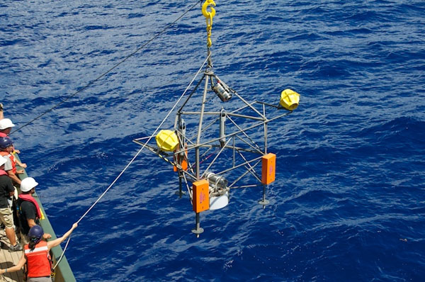 The time-lapse camera tripod is lifted over the railing of Lone Ranger and lowered into the ocean. The deep-sea observatory will rest on the seafloor for the next six months, collecting particle samples and recording images of the depths.