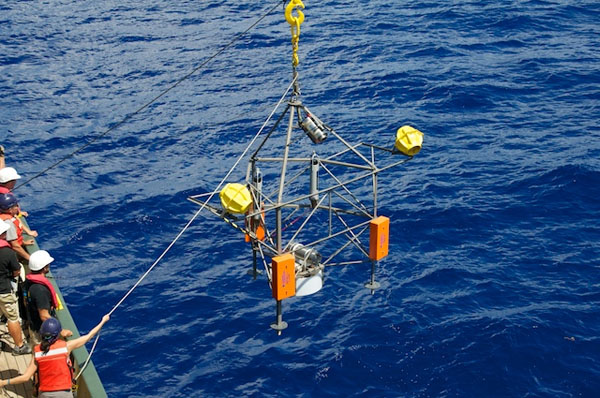 The time-lapse camera tripod is lifted over the railing of Lone Ranger and lowered into the ocean. The deep-sea observatory will rest on the seafloor for the next six months, collecting particle samples and recording images of the depths.
