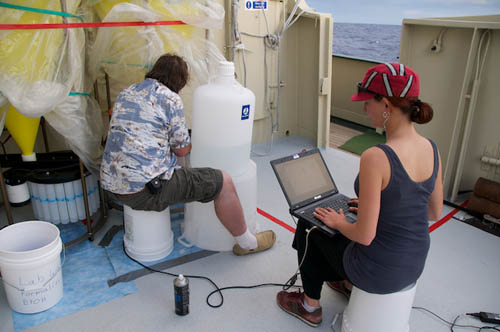 Jake Ellena and Judit Pungor set-up the sample bottles for the sediment traps. Judit uses the computer to rotate the carousel of bottles that Jake is filling with sample preservative.