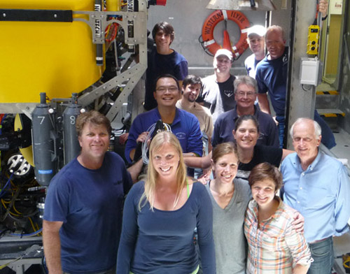 The science team and ROV pilots pose in front of ROV Doc Ricketts in the moon pool. Front row: Randy Prickett, Susan von Thun, Ally Pasulka, Kat Dawson, Peter Brewer. Middle: Xin Zhang, Ed Peltzer, Victoria Orphan. Back: Ben Erwin, Bryan Schaefer, Peter Walz, Mark Talkovic, Knute Brekke.