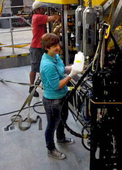 Kat retrieves water from the Niskin bottle after the dive. Victoria’s group will filter this water to look for methane-oxidizing microbes that live in the water column. Marko works on the Ricketts in the background.