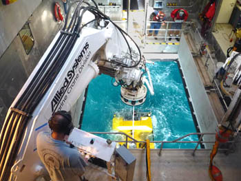 The view of Doc Ricketts recovery from a window on the second deck. Lower left, Erik Larson controls the crane, in the far right, Knute and Marko watch as the ROV comes into their view.