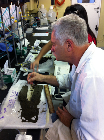 In the ship's wet lab we often extrude the sediment from the push cores, put them on a labeled tray, cut them in half, and photograph them. Charlie Paull is examining the layers present in one of the cores.
