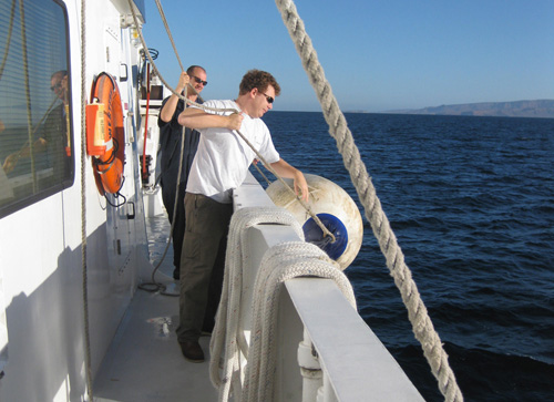 Jason Jordan, left, and Andrew McKee lower a fender into place in preparation for docking in Pichilingue.