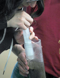 Abbey uses a syringe to extract the water sample from the top of the push-core sample.