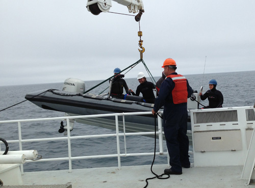 Engineer Olin Jordan holds a line to the RHIB as the crane lowers it over the side. For more on blue-water diving, see yesterday's log.