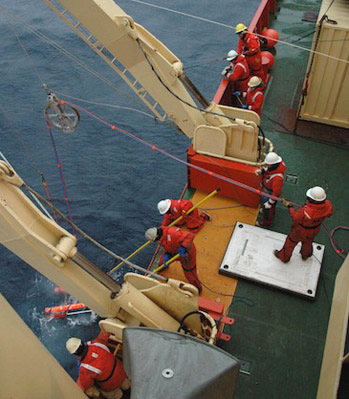 ROV IceCUBE being retrieved from the ocean. The clear tubing, taped to the red tether, pumps clean seawater back to the ship. Photo by Larry Lovell.
