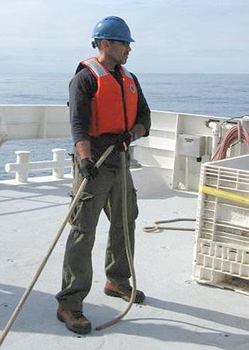 Rich Henthorn helps steady the sediment traps as they come onboard the Western Flyer. Pulling equipment from the water requires teamwork to safely move heavy equipment out of the water onto a moving ship. Photo: Paul McGill.