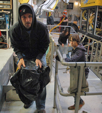 Chris carries the covered suction sampler bucket with Alicia right behind. Kris Walz is in the background removing another bucket from the carousel.