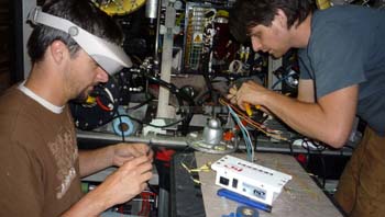 Bryan Schaefer and Ben Erwin have their work cut out for them as they carefully re-terminate the fiber-optic tether on the rocking ship.