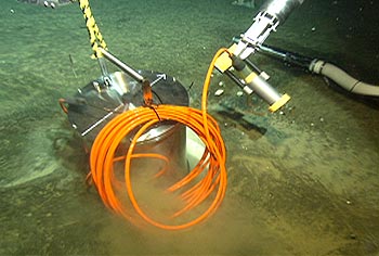 This photo shows the titanium pressure housing for the MOBB seismometer being lowered into a protective casing in the seafloor. This ultra-sensitive instrument was first installed in Monterey Bay in 2002. The seismometer operated on batteries (which had to be changed every three months) until it was hooked up to the MARS observatory in early 2009. Image: (c) 2002 MBARI