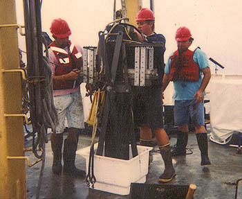 Researchers collect a box core of sediment from the Santa Barbara Basin. To collect a box core, a metal box, about a meter and a half long and 20 centimeters wide, is lowered down to the sea bottom, where it sinks into the soft sediment. After the box core is brought back to the surface, undisturbed layers of sediment can be collected from the inner portion of the core. Image: (c) 1997 Vicente Ferreira-Bartrina