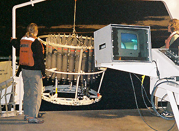 MBARI researchers collected large volumes of seawater using circular arrays of Niskin bottles such as this one (the ring of gray plastic cylinders). The lids of these bottles are left open as the array is lowered down into the ocean. When the array reaches the desired depth, the bottles are closed remotely so that the water from that depth can be brought back to the surface. Image: Lynne Christianson (c) 2002 MBARI