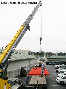 In May 2005, the trawl-resistent frame for the MARS node was delivered to MBARI on a large flatbed truck. This was no easy ride, since the frame is about twelve feet wide, fifteen feet long, and four feet tall. Here the frame is waiting to be transferred into a staging area at MBARI (the cars nearby had to be moved first). Image: Lisa Borok (c) 2005 MBARI