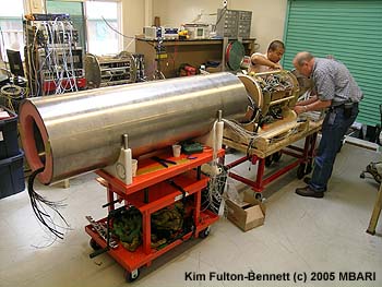 In early August 2005, MBARI electronics technicians Dick Littlefield and Jose Rosal prepared the wiring for the MARS data hub and power-supply. The completed package will sit inside the long stainless steel cylinder, which is designed to protect the delicate electronics from the crushing pressure of the deep sea. Image: Kim Fulton-Bennett (c) 2005 MBARI