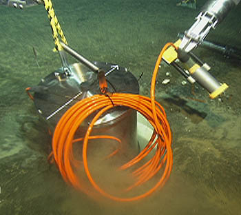 This image taken by ROV Ventana shows the MOBB seismometer being lowered into a plastic sleeve in the seafloor, about 1,000 meters below the surface of Monterey Bay. The seismometer was buried in the seafloor to shield it from the tiny vibrations caused by ocean-bottom currents and waves at the ocean surface. Image: (c) 2002 MBARI