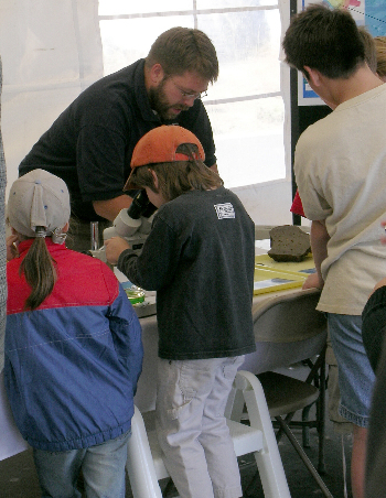 A budding young scientist peers through the microscope at rock samples, while geologist Joel Johnson explains the exhibit. Photo: Kim Fulton-Bennett (c) 2004 MBARI