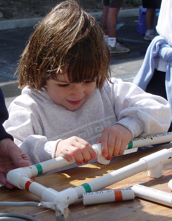 A young girl concentrates on building her own remotely operated vehicle out of PVC pipe. Photo: Duane Thompson (c) 2004 MBARI