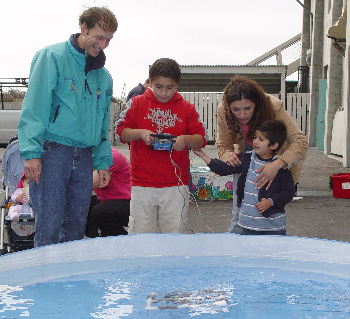 MBARI engineer Brent Roman, left, helps a family test a small remotely operated vehicle (ROV) that they made themselves. Photo: Duane Thompson (c) 2004 MBARI