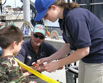 Ian Young, master of the Research Vessel Point Lobos and Research Assistant Marguerite Blum show a visitor styrofoam cups that have been carried down to the ocean depths by MBARI's remotely operated vehicles. The immense pressure of the deep ocean causes these cups to shrink to one third of their original size. Photo: Heather Fulton-Bennett (c) 2007 MBARI