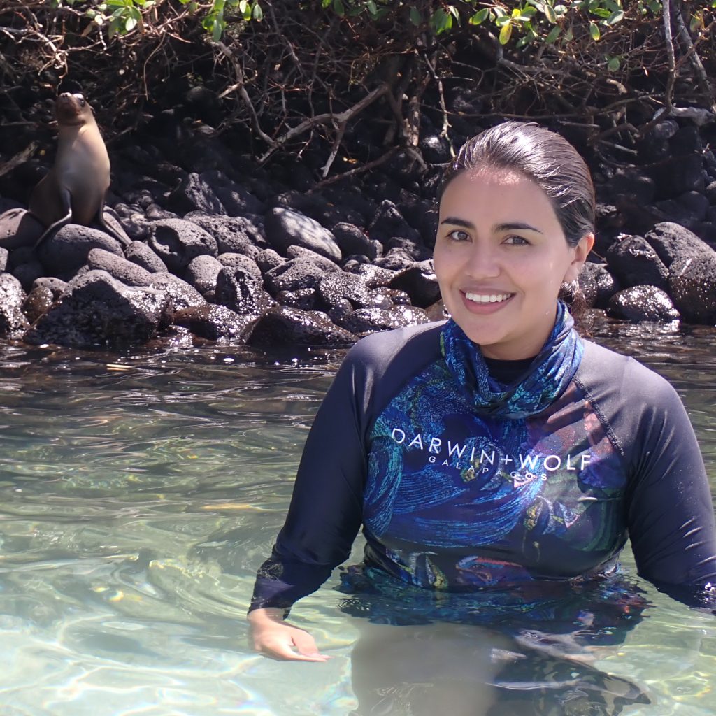 image on Ana Belen Yanez Suarez in the water with a galapagos fur seal behind her on the rocks