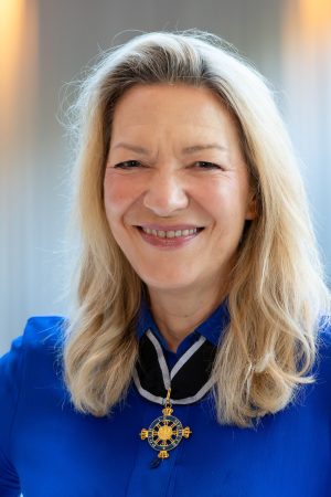 A portrait of MBARI President and CEO Antje Boetius following an award ceremony. She is wearing a medal with a gold-and-blue metal cross on a black ribbon with silver trim. The background is a white wall.