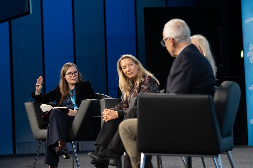Four people sit for a panel discussion inside a large auditorium during an international geopolitical conference.