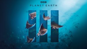 Promotional art for the Planet Earth III series featuring the BBC logo with B, B, and C in black boxes, the text “Planet Earth” in uppercase black letters, and three transparent vertical rectangles representing the Roman numeral three. The background is light blue with a screen capture from underwater video of a school of pygmy devil rays. Larger images of six pygmy devil rays are layered on top of the Roman numeral three, as if swimming out of the three rectangles.