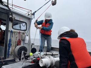 Two scientists onboard a small boat preparing the deploy an instrument