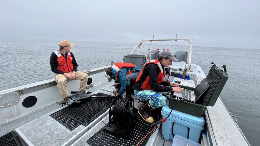 Sasha Kramer preparing a hyperpro radiometer on board the Paragon, along with other members of the Carbon Flux Ecology team.