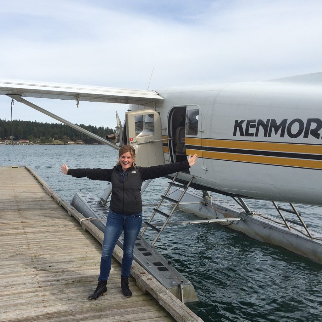 Emma Riley stands in front of a seaplane